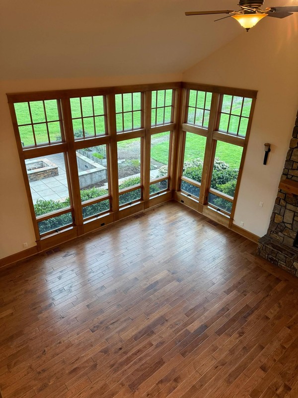 Bright windowed room with clean hardwood flooring and clear views across the surrounding landscaped grounds.