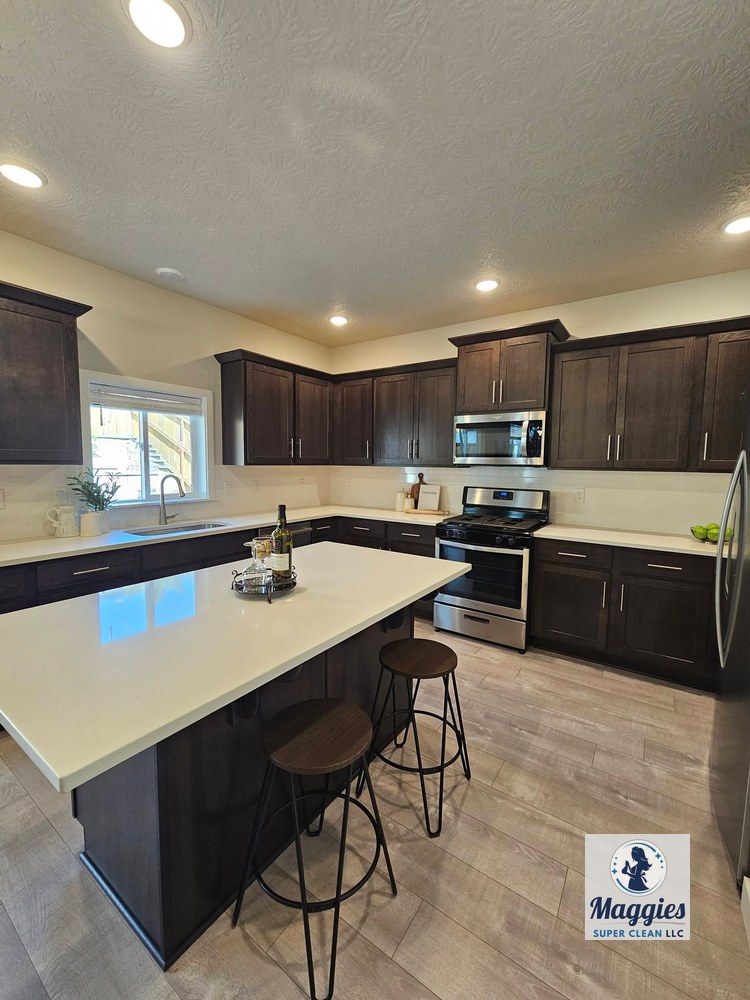 The kitchen has a polished, orderly appearance, with countertops, cabinetry, appliances, island surfaces, and flooring presented cleanly after the residential deep cleaning.